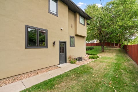 Exterior view of a modern house with a light beige stucco finish and dark window trims.