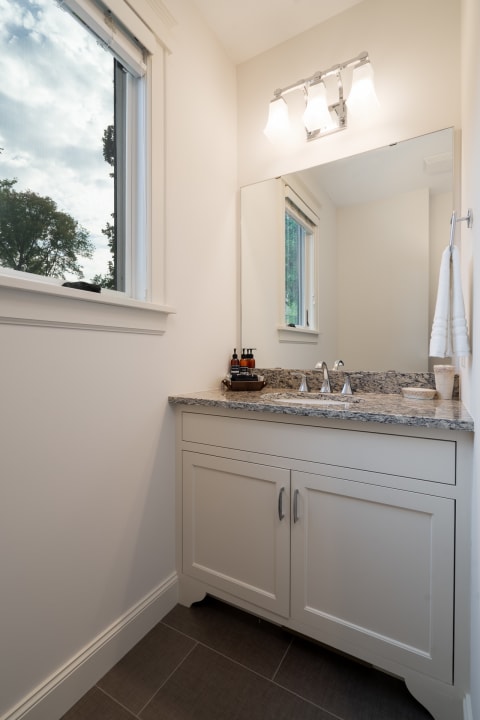 A contemporary bathroom with a granite countertop, polished chrome faucets, and a mirror.