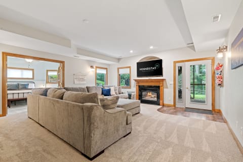 A spacious living room featuring a sectional sofa, fireplace, and a mounted TV.