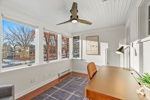 Bright workspace with wooden desk and white walls, featuring large windows and modern decor.