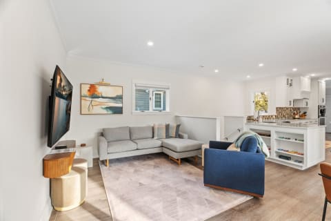 Modern living room featuring a gray sectional sofa, navy armchair, and abstract artwork.