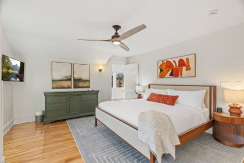 A modern bedroom with a bed, artwork, and wooden furniture, creating a serene atmosphere.