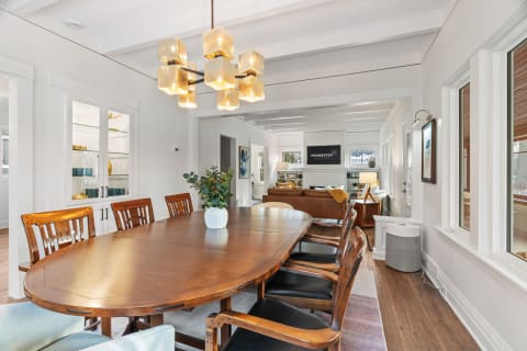 A modern dining area with a wooden table, stylish chairs, and a warm pendant light, blending with a cozy living space.
