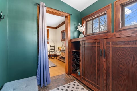 Entryway with green walls, a fabric curtain, and wooden furniture.