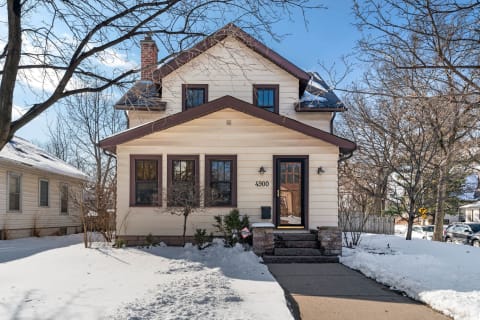 Two-story house surrounded by snow in a winter landscape.