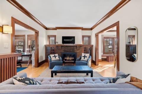 Cozy living room with blue armchairs, a rustic coffee table, and a brick fireplace.