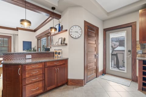 Cozy kitchen corner featuring wooden cabinetry, pendant lighting, and a doorway leading outside.