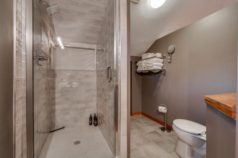 Modern bathroom with glass shower and white towels on a shelf.