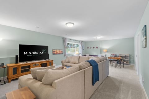 Cozy living room with a beige couch, television, and a dining table.