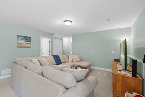 Cozy living room featuring a beige sectional sofa, a wooden TV stand, and light green walls.