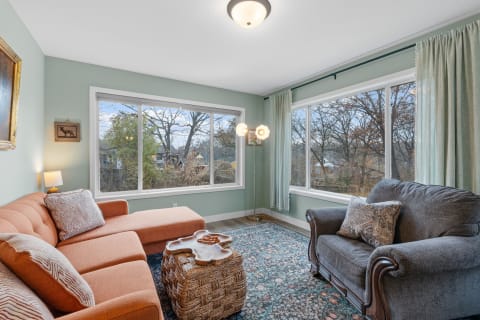 Cozy living room with a terracotta sectional sofa, grey armchair, and large windows.
