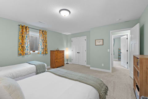A serene twin bedroom with two beds, bright curtains, and wooden furniture.