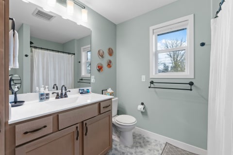 Modern bathroom with light green walls, white sink countertop, and decorative plates.