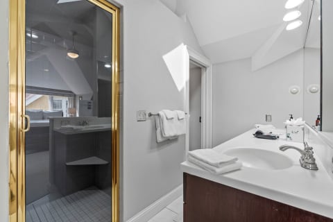 Stylish bathroom featuring a gold-framed shower door, smooth countertop, and neatly arranged towels.