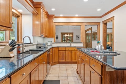 Bright kitchen featuring wooden cabinets and a granite countertop with a stove and sink.