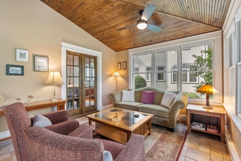 Cozy living room with olive-green sofa and burgundy armchairs under a wooden ceiling.