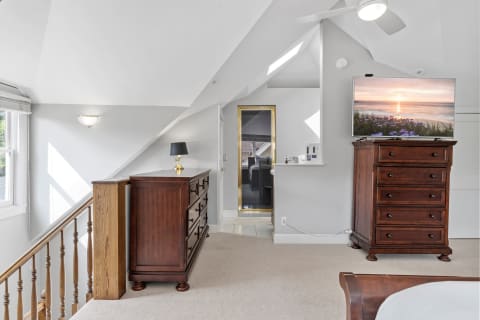 Bright bedroom with a wooden dresser, lamp, and TV displaying a sunset.