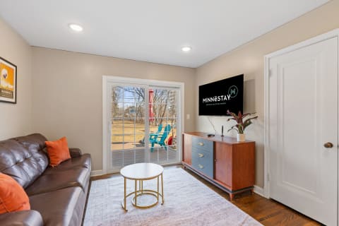 Living room with leather couch, coffee table, and TV displaying MINNESTAY.