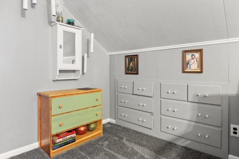 Interior of a room featuring a green dresser, gray drawers, and framed artworks on the wall.