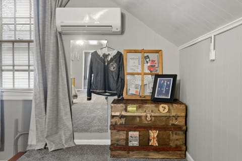 Cozy room corner featuring a vintage trunk, a framed photo, and a hanging shirt.