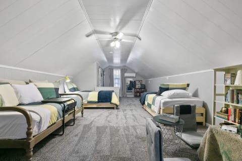 A spacious attic room with three beds, modern seating, and a cozy atmosphere.