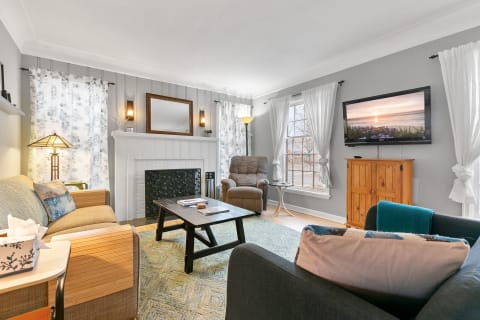 A well-decorated living room featuring a couch, coffee table, and a TV against a soft gray wall.