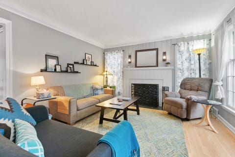 A living room featuring a mix of modern and cozy elements, including sofas, a coffee table, and a fireplace.