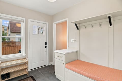 A bright mudroom with built-in storage, wall hooks, and a bench for shoe storage.