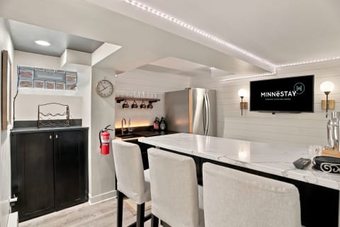 Modern kitchen featuring marble countertops, bar seating, and contemporary lighting.