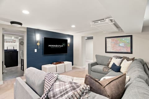 A stylish basement entertainment room with gray sectional, navy wall, and decorative accents.