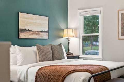 Plush bed with white linens and a teal accent wall in a cozy bedroom setting.