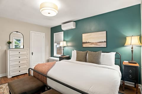 A cozy bedroom with teal walls, a white bed, and warm lighting creating a tranquil atmosphere.