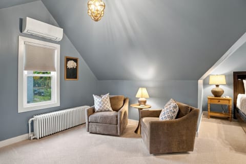 A serene corner with two upholstered armchairs and soft lighting beneath a sloped blue ceiling.