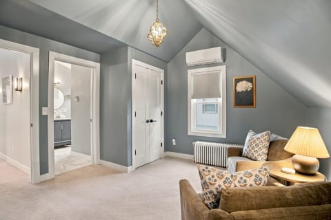 A cozy upstairs room with gray walls, plush sofas, and a warm lamp, creating a peaceful ambiance.