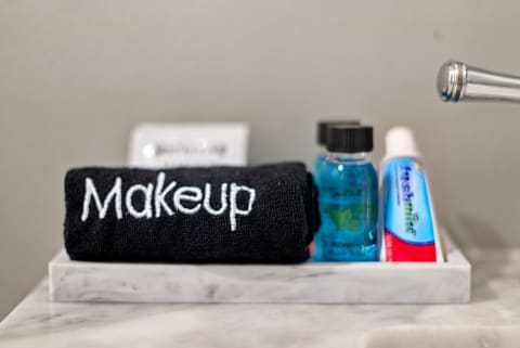 A marble tray displays a black towel labeled 'Makeup', a bottle of mouthwash, and a tube of toothpaste, creating a stylish bathroom scene.