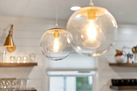 Two elegant transparent pendant lights hang in a modern kitchen, casting a warm glow over the space.