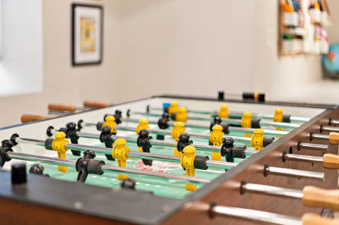 A close-up view of a foosball table with yellow and black players ready for a match.