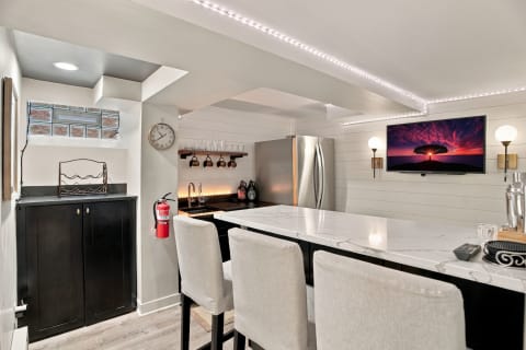 Modern kitchen-bar area with marble island, stainless steel refrigerator, and cozy lighting.