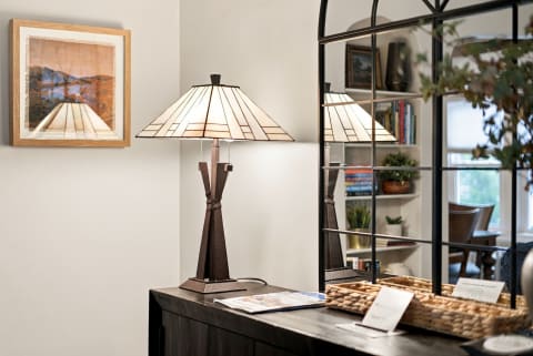 A beautifully decorated corner of a living room with a lamp, mirror, and artwork.