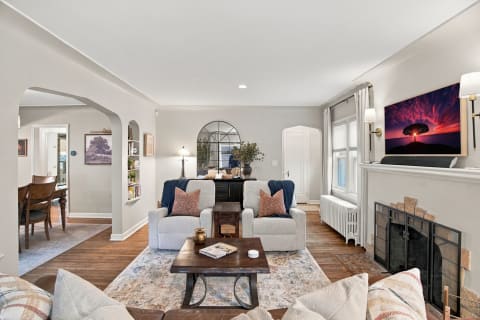 A cozy and elegant living room featuring armchairs, a coffee table, and a fireplace.