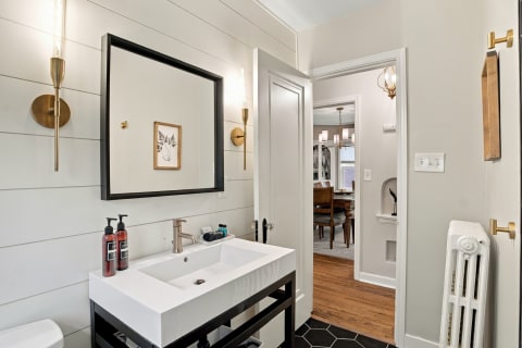 Modern bathroom featuring a pedestal sink, shiplap walls, and elegant lighting.
