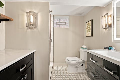 Modern bathroom featuring white countertops, black cabinets, and stylish tile flooring.
