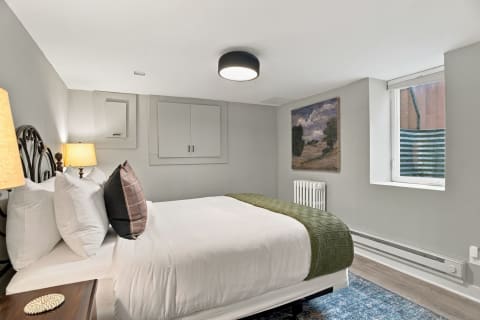 A modern bedroom with a white bed, green throw, soft lighting, and calming decor.