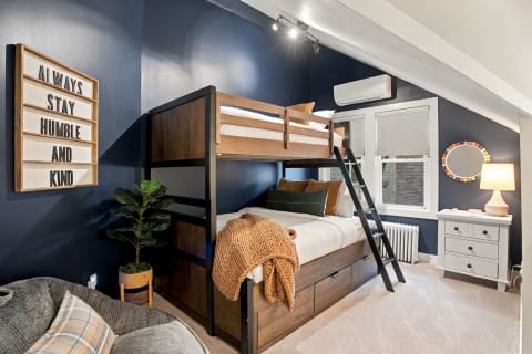 Cozy bedroom with a custom bunk bed, navy walls, and a motivational sign.