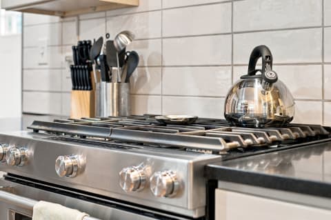 Close-up of a modern gas range with a kettle and kitchen utensils in a stylish kitchen.