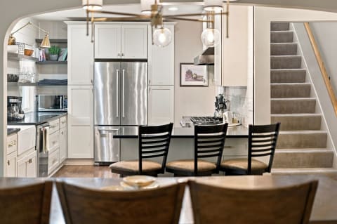 Open-concept kitchen featuring stainless steel appliances, black countertops, and a cozy dining area with bar stools.