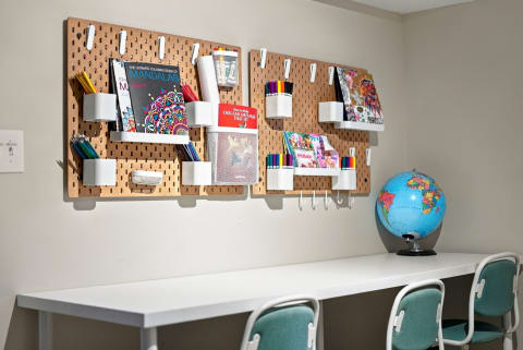 A bright and organized creative workspace with pegboards of art supplies and a globe, designed for focused projects.