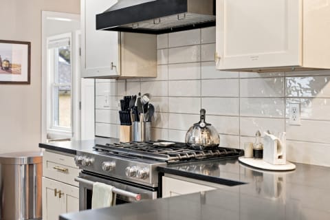 Modern kitchen scene showcasing a gas range, granite countertops, and neatly arranged kitchenware.