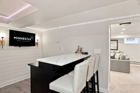 Modern bar area with marble countertop, LED lighting, and comfortable seating.