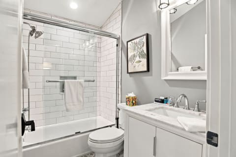 A modern bathroom with white subway tiles, marble-topped vanity, and contemporary decor.